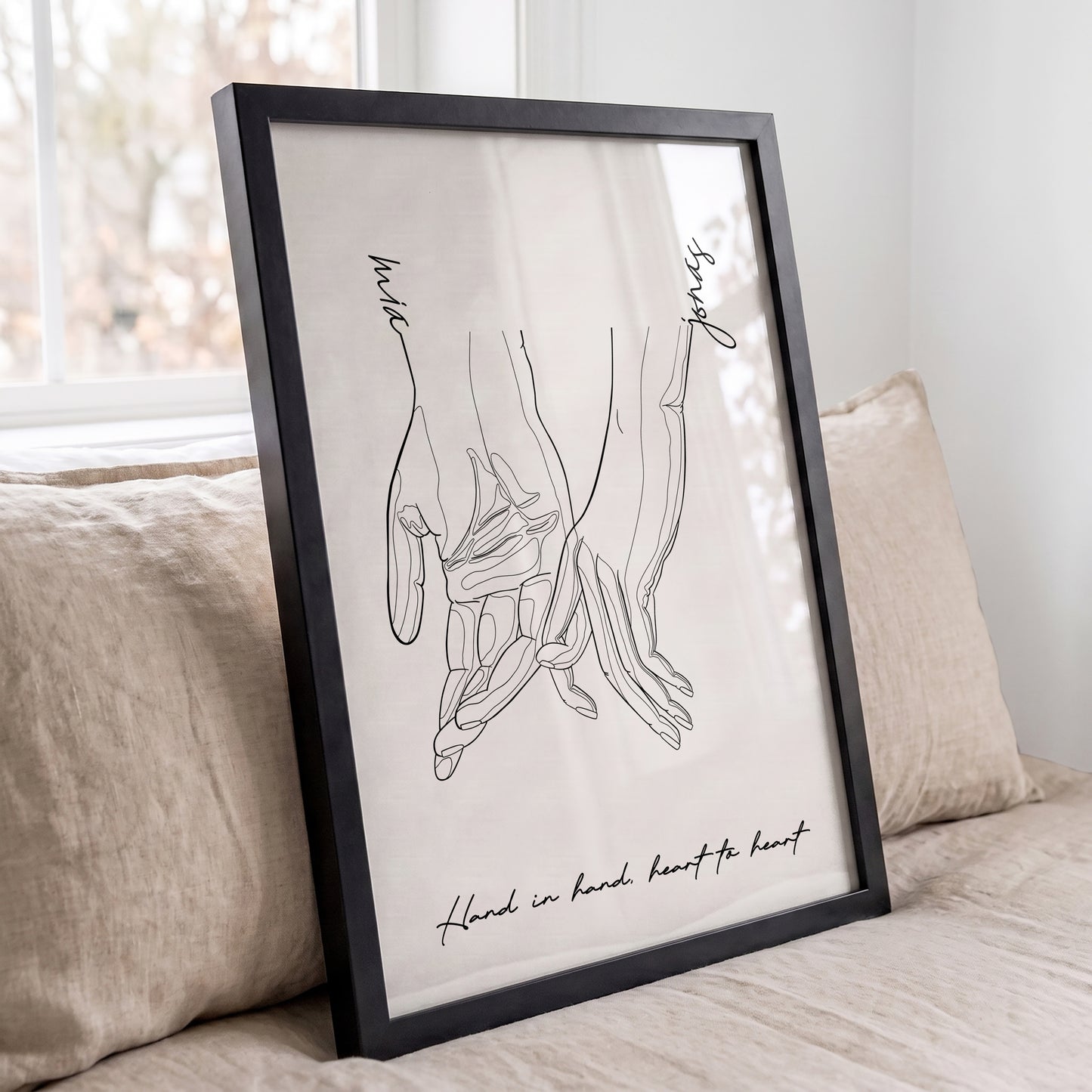 Minimalist personalized couple wall art in a black frame featuring holding hands line art.