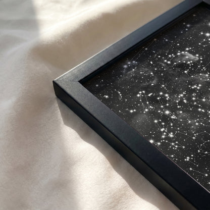 Close-up of a personalized cloud background star map print resting on a soft, sunlit cream-colored fabric surface.
