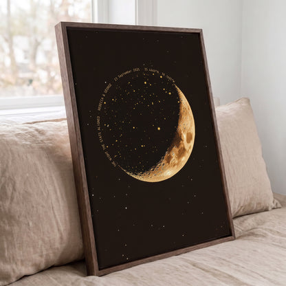 Personalized moon phase star map displayed in a dark wood frame on a bed
